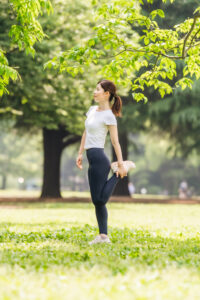 Woman doing a gentle quad stretch outdoors with natural posture and balance.
